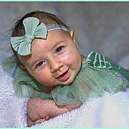 Harper joined the competition — help win amazing prizes! baby, infant, smile, bow_headband, green_dress, tulle, blanket, fluffy, cheeks, blue_eyes, portrait, closeup, adorable, happy, hand, skin, soft_texture, studio_style, cute, lying_down