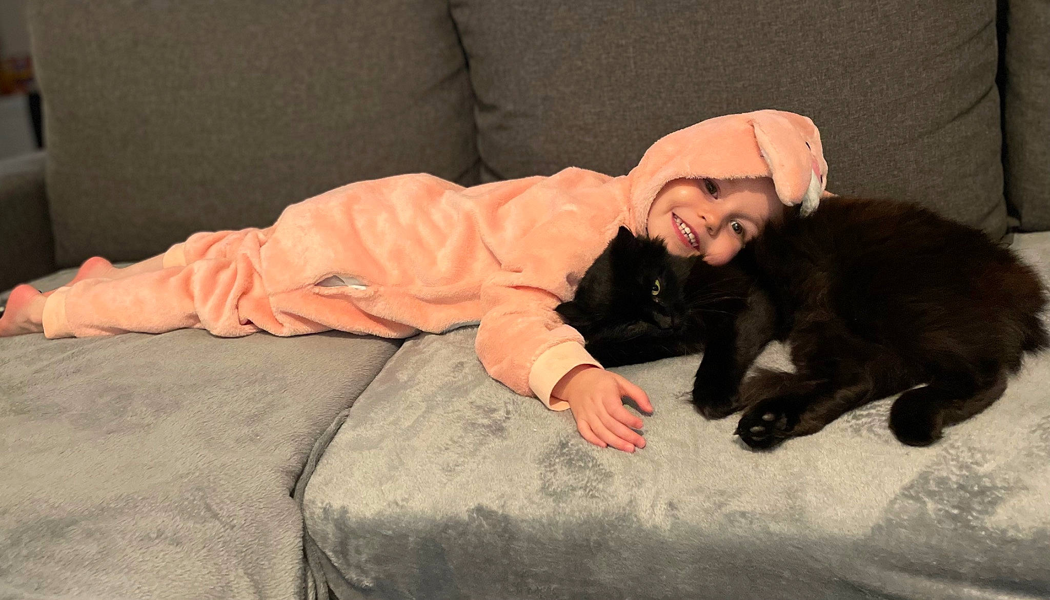 Carla participe au concours pour gagner de l'argent avec cette photo : bed, bedding, carnivore, cat, child, comfort, companion_dog, domestic_short_haired_cat, felidae, flooring, fun, fur, headwear, joy, linens, person, room, sitting, smile, toddler