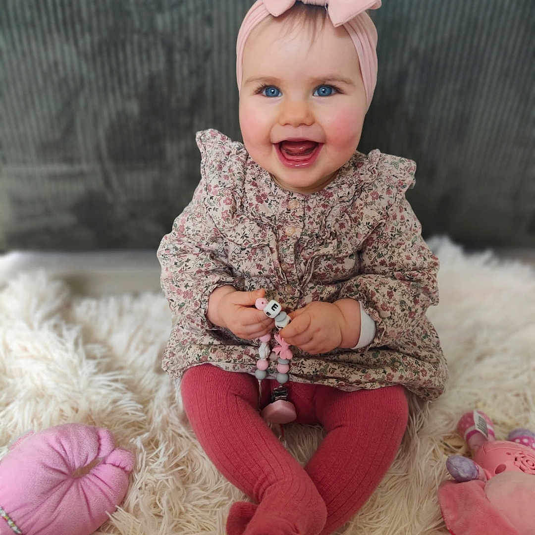 Haneïa a rejoint le concours — aidez-le/la à gagner de superbes lots ! adorable, baby, beads, blue_eyes, child, closeup, cute, floral_dress, happy, headband, indoor, infant, pink_bow, pink_tights, playful, portrait, rug, sitting, smiling, toy