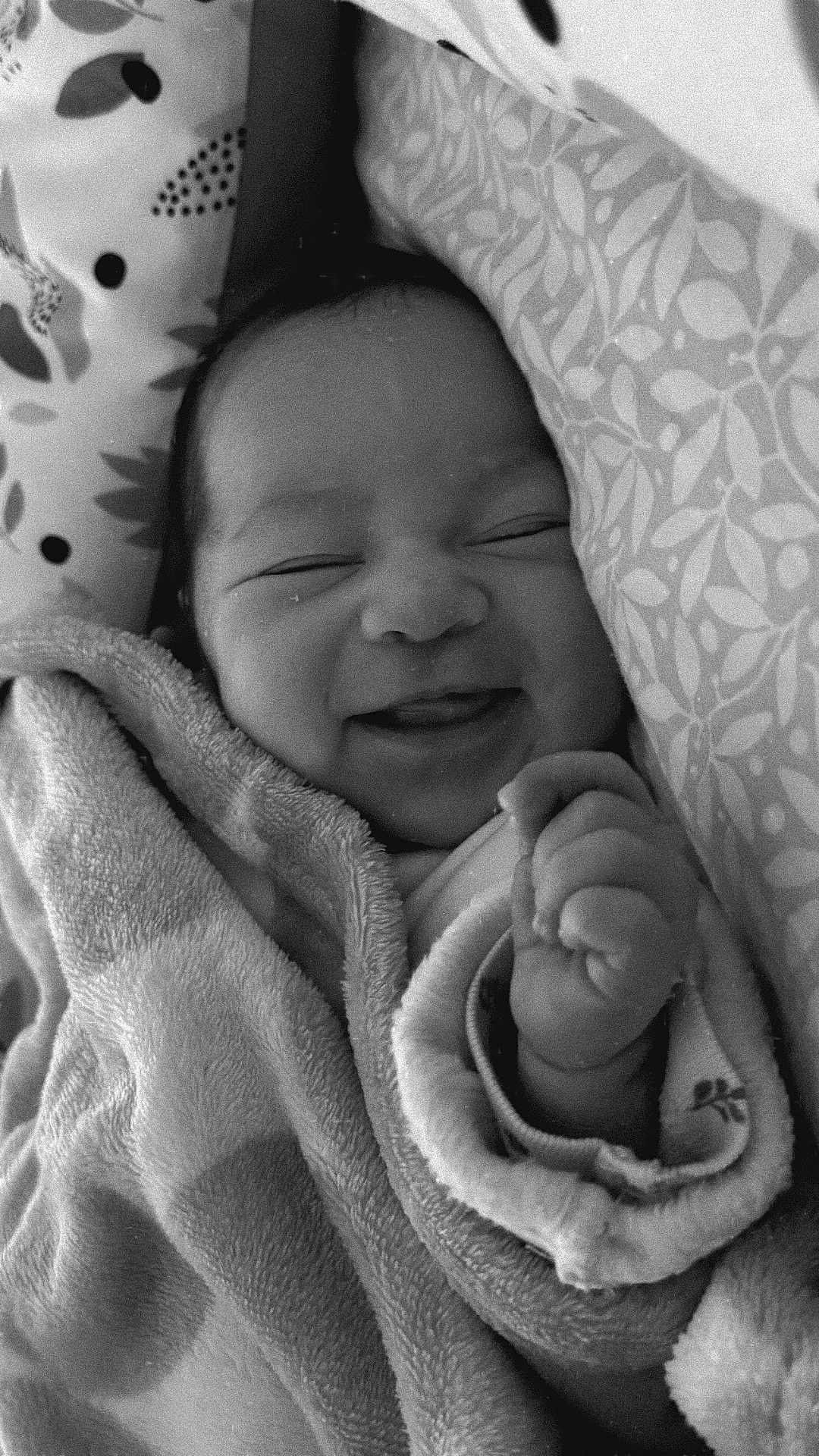 Béatrice a rejoint le concours — aidez-le/la à gagner de superbes lots ! baby, newborn, smiling, blanket, cozy, black_and_white, sleeping, infant, cute, peaceful, wrapped, soft_texture, hand, face, indoors, portrait, bed, pattern, closeup, comfort