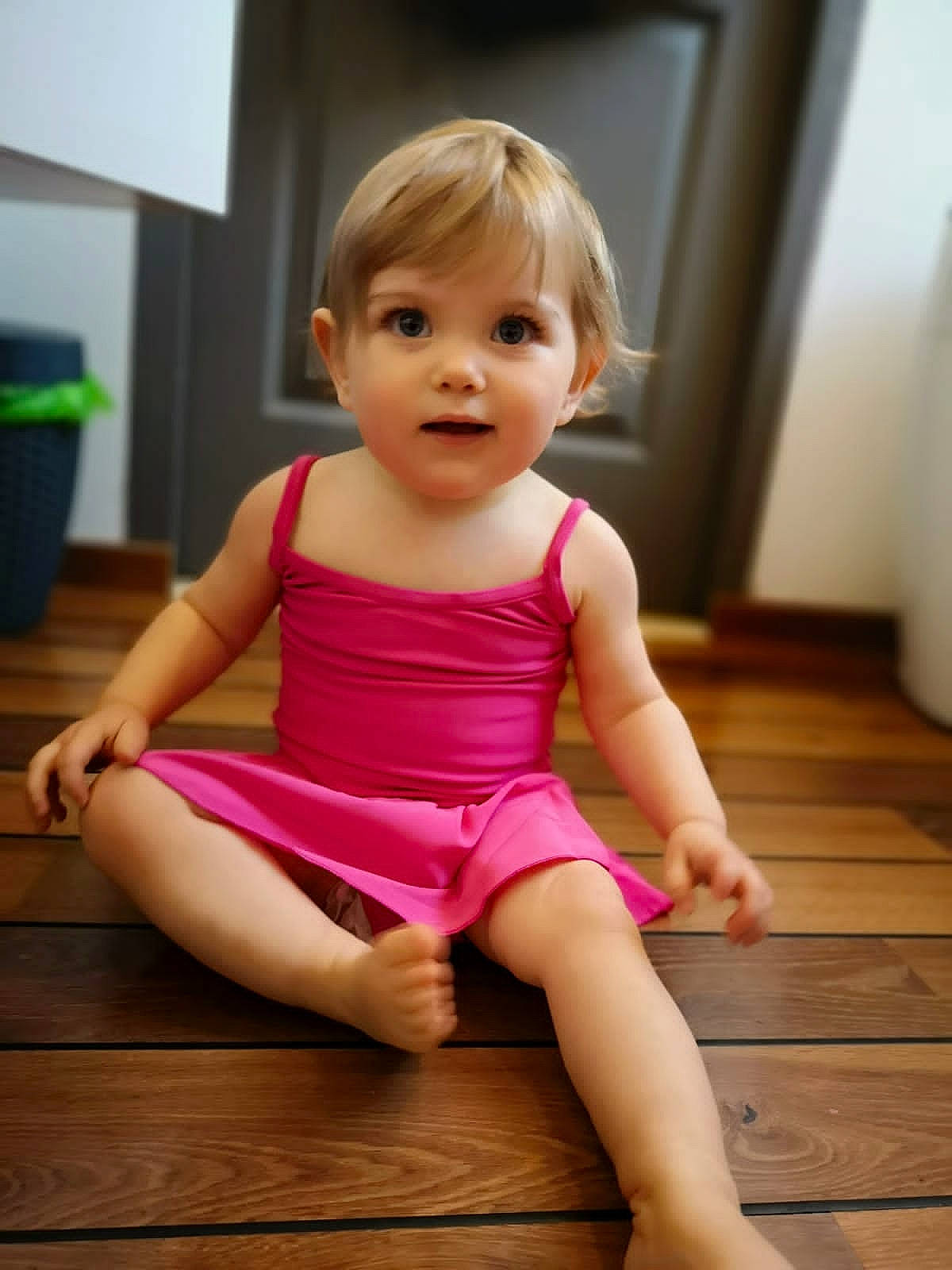 Iris participe au concours pour gagner de l'argent avec cette photo : baby_toddler_clothing, cheek, dress, floor, flooring, fun, hardwood, human_leg, joint, leg, one_piece_garment, person, pink, shoulder, skin, sleeve, smile, thigh, thumb, toddler