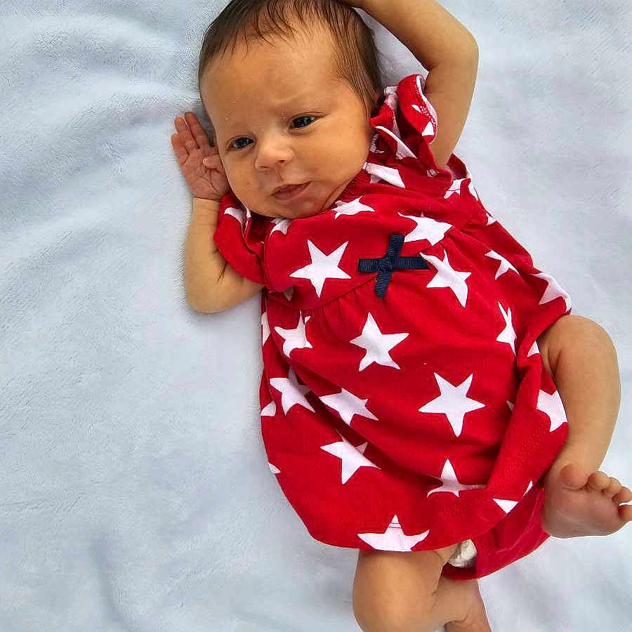 Alexandra joined the competition — help win amazing prizes! americanflag, baby, bed, blanket, bodypart, clothing, dress, face, finger, flag, hand, happy, head, newborn, person, photography, portrait, quilt, smile, t_shirt