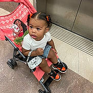 Amarie joined the competition — help win amazing prizes! toddler, child, stroller, shoes, orange, hair_ties, purse, white_shirt, denim_shorts, earrings, floor, elevator, curly_hair, indoor, person, expression, looking_away, accessories, cartoon_character, moana