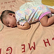 Jayleen is registered to the contest to win money with this photo: baby, sleeping, blanket, floral_onesie, infant, cute, peaceful, soft, lying_down, indoors, child, small, resting, head, face, legs, skin, comfort, cozy, nap