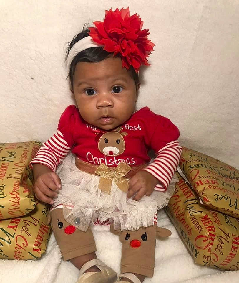 Kemoni is registered to the contest to win money with this photo: baby, baby_toddler_clothing, child, child_model, costume_accessory, fur, hair_accessory, headband, headgear, headpiece, home_accessories, human_body, living_room, mammal, mouth, nose, person, petal, pink, sock