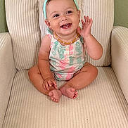 Eris is registered to the contest to win money with this photo: baby, child, smiling, sitting, armchair, headband, bow, romper, seahorse_print, pastel_colors, happy, cute, indoors, furniture, toe, hand, earrings, portrait, infant, expression