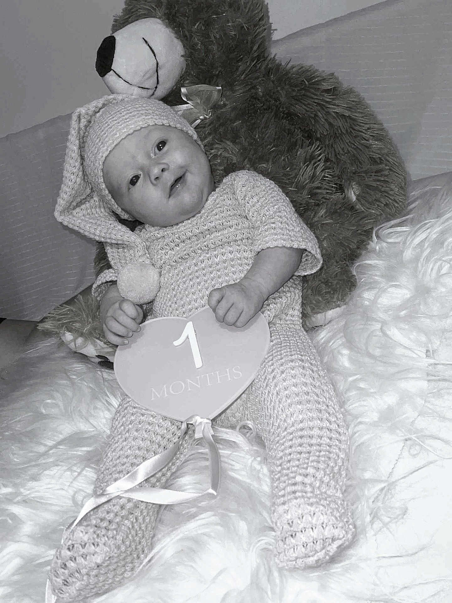 Apolline a rejoint le concours — aidez-le/la à gagner de superbes lots ! baby, infant, knitted_outfit, hat, teddy_bear, soft_texture, blanket, heart_shaped_sign, 1_month, cute, smiling, cozy, indoor, portrait, child, newborn, resting, fuzzy, warm, happy