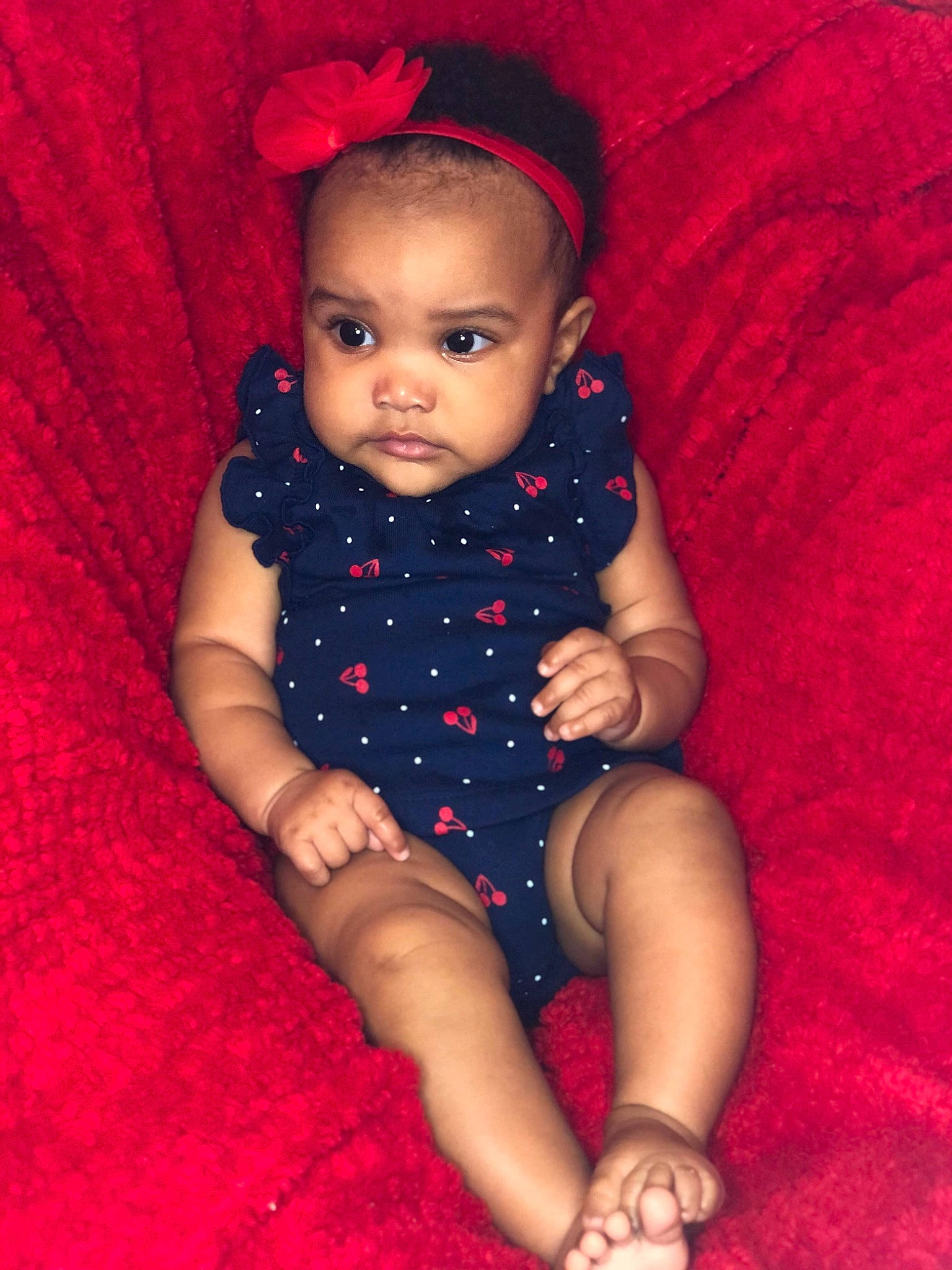 Elle is registered to the contest to win money with this photo: baby, baby_toddler_clothing, cheek, child, comfort, costume_accessory, finger, foot, hair_accessory, headband, headpiece, human_body, lip, nail, nose, person, red, skin, textile, toddler