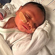 Malakai is registered to the contest to win money with this photo: newborn, baby, sleeping, hospital, medical_tape, feeding_tube, white_clothing, blanket, infant, face, peaceful, resting, bed, healthcare, soft, cute, child, person, closeup, indoors