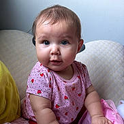 Nelsy joined the competition — help win amazing prizes! baby, child, infant, portrait, sitting, indoors, smiling, curious, serious_expression, face, eyes, pink_clothing, strawberry_pattern, plush_toy, stuffed_animal, blanket, cushion, cozy, home, photography