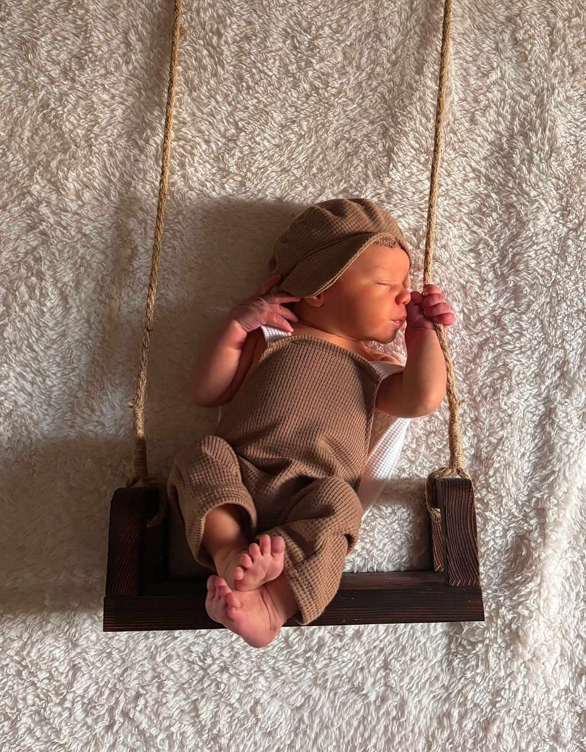 Hudson joined the competition — help win amazing prizes! newborn, baby, sleeping, swing, rope, wood, brown_clothing, hat, blanket, cozy, infant, peaceful, portrait, soft_texture, indoor, cute, resting, small_feet, child, warm_lighting