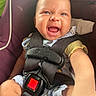 baby, infant, child, smiling, happy, laughing, face, portrait, car_seat, safety_harness, seatbelt, vehicle, indoor, close_up, sitting, blue_clothing, yellow_sleeve, brown_eyes, infant_carrier, joy
