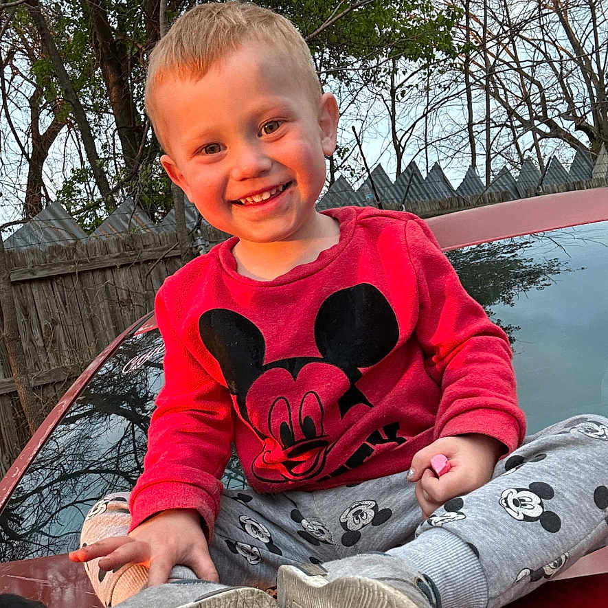 Logan joined the competition — help win amazing prizes! boy, child, clothing, face, footwear, happy, head, male, pants, person, photography, plant, portrait, shoe, sitting, smile, t_shirt, tree, water, waterfront