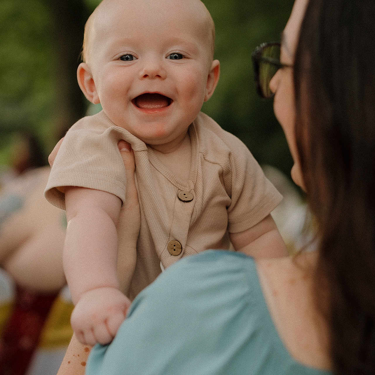Judson is registered to the contest to win money with this photo: baby, buttoned_shirt, casual, child, clothing, daylight, expression, face, greenery, hand, happy, holding, outdoor, person, portrait, short_hair, shoulder, skin, smiling, woman