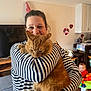 baby, bracelet, cat, child, decorations, furniture, holding, home, indoor, living_room, orange_cat, pet, play_area, smile, striped_clothing, television, watch, watching, woman, wooden_floor