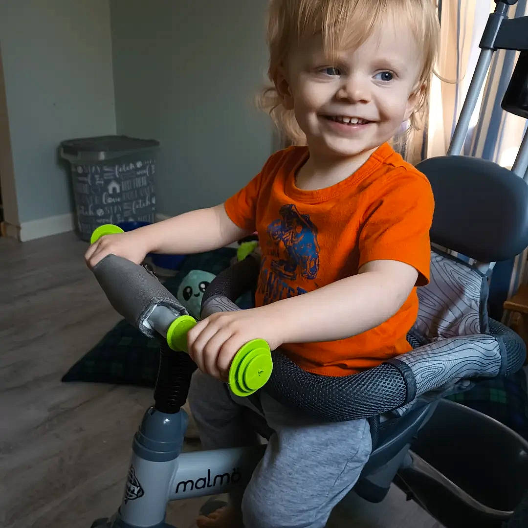 Carsyn is registered to the contest to win money with this photo: baby, baby_products, baby_toddler_clothing, chair, child, comfort, human_leg, joy, knee, lap, machine, person, riding_toy, sitting, smile, sock, t_shirt, thumb, tire, toddler