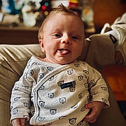 William participe au concours pour gagner de l'argent avec cette photo : baby, bear_pattern, child, clothing, cozy, cute, expression, face, hand, indoor, infant, person, portrait, relaxed, sitting, smiling, soft_lighting, tongue_out, warm_tones, young