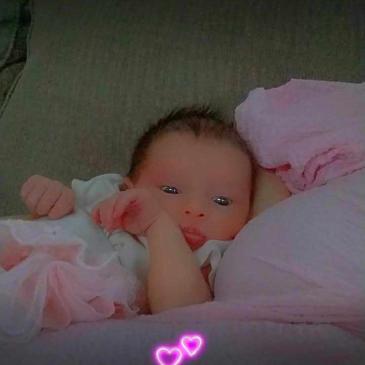 Trishlynn is registered to the contest to win money with this photo: baby, infant, couch, blanket, pink, heart, neon, glow, soft, cozy, relaxing, cute, clothing, person, portrait, indoors, newborn, resting, hand, face