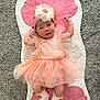 Angelina is registered to the contest to win money with this photo: baby, tutu, headband, flower, pink, peach, socks, rug, carpet, smile, infant, cute, child, lying_down, soft, fabric, playful, indoors, happy, portrait