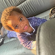 Tre'Mir joined the competition — help win amazing prizes! toddler, child, baby, curly_hair, blue_clothing, onesie, car_seat, leather, sunlight, playful, reaching, face, portrait, young_child, indoor, seat, person, cute, expression, small