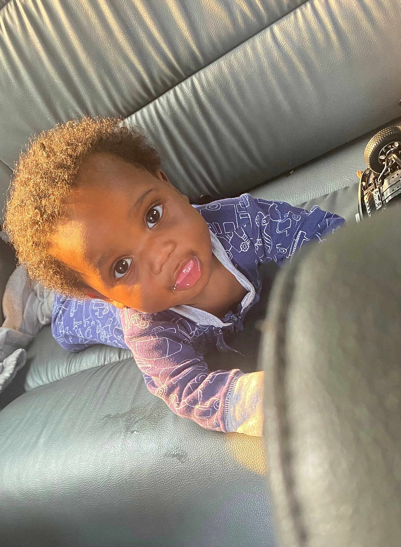 Tre'Mir joined the competition — help win amazing prizes! toddler, child, baby, curly_hair, blue_clothing, onesie, car_seat, leather, sunlight, playful, reaching, face, portrait, young_child, indoor, seat, person, cute, expression, small