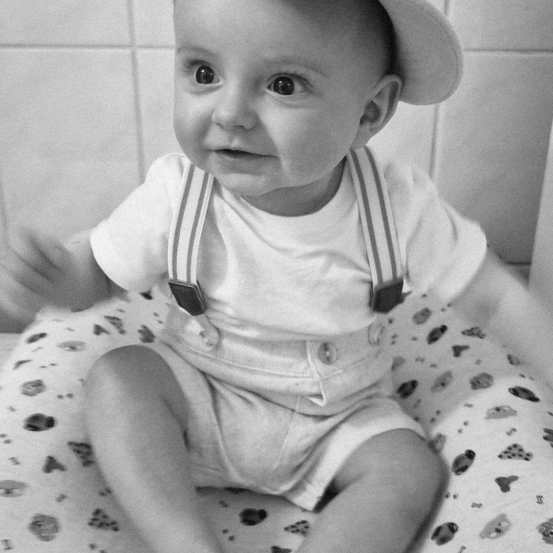 Sacha a rejoint le concours — aidez-le/la à gagner de superbes lots ! baby, child, clothing, cushion, cute, eyes, face, hands, happy, hat, indoor, infant, legs, pattern, portrait, shorts, sitting, smiling, suspenders, white_shirt