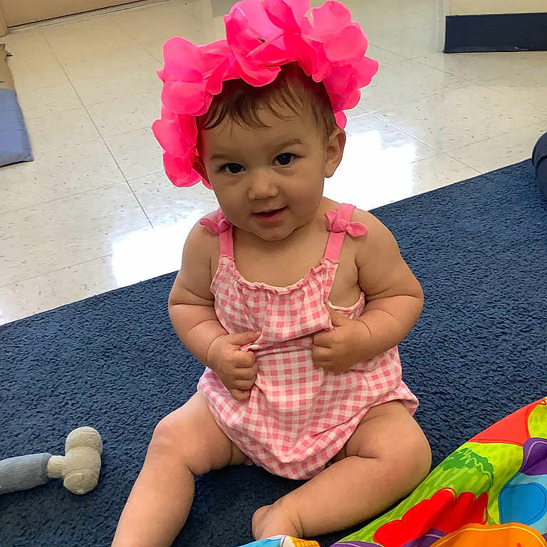 Anneliese is registered to the contest to win money with this photo: accessories, baby, bodypart, cap, clothing, costume, dress, face, finger, flower, hand, hat, head, indoors, person, photography, plant, portrait, shorts, sitting