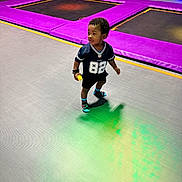 Willie is registered to the contest to win money with this photo: child, kid, trampoline_park, indoor, colorful, sporty_clothing, socks, toy, playing, curious, floor, purple_padding, active, young, person, fun, recreation, leisure, casual, footwear