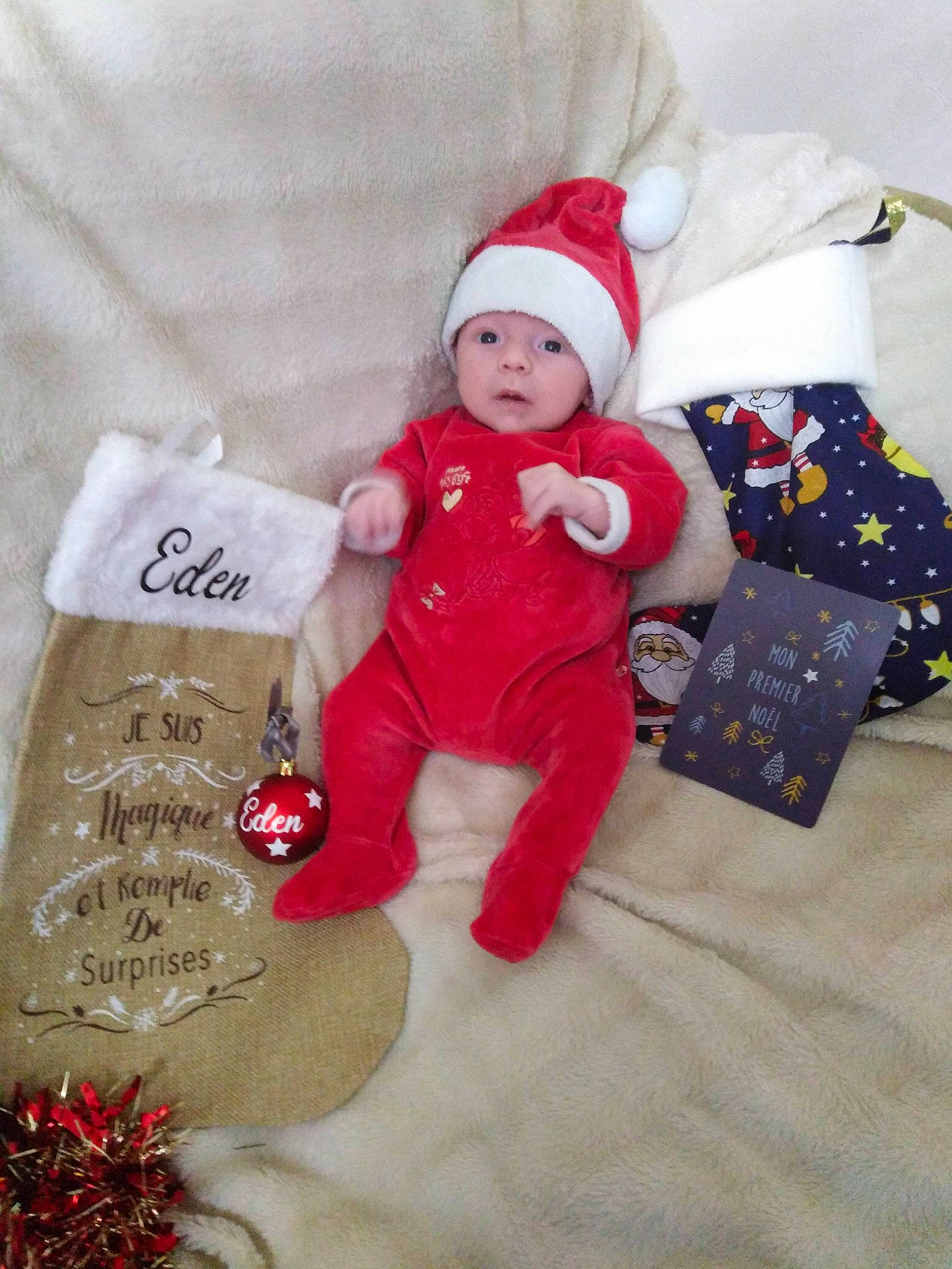 Éden a rejoint le concours — aidez-le/la à gagner de superbes lots ! baby, baby_toddler_clothing, carmine, christmas, christmas_decoration, christmas_eve, christmas_ornament, comfort, costume_hat, event, face, headwear, holiday, holiday_ornament, linens, person, red, sleeve, sock, stuffed_toy