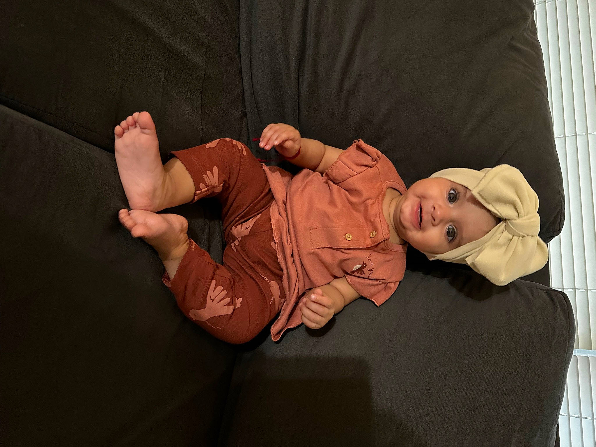 Estella is registered to the contest to win money with this photo: abdomen, baby, child, comfort, elbow, eye, foot, fun, hat, headwear, human_leg, knee, lap, linens, person, room, sitting, sock, thigh, toddler