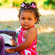 Layana a rejoint le concours — aidez-le/la à gagner de superbes lots ! book, butterfly_clips, child, curly_hair, cute, daylight, grass, hair_clips, nature, outdoor, person, pink_dress, playful, portrait, purple_chair, reading, smiling, summer, toddler, young_child
