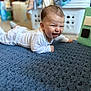 baby, child, smiling, pajamas, lying_down, blue_rug, indoor, home, happy, face, infant, crawling, person, carpet, texture, cozy, cute, playful, young_child, expression