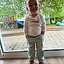 Nino participe au concours pour gagner de l'argent avec cette photo : toddler, child, smiling, indoor, glass_door, casual_pose, white_shirt, pants, sandals, toy_keys, backyard, playground, slide, swing, tree, greenery, wooden_floor, happy, portrait, daylight