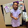 Demi is registered to the contest to win money with this photo: child, girl, smile, purple_clothing, bow, bracelets, drawings, fridge, floor, indoor, happy, person, sandals, artwork, home, wall, plastic_bags, cute, young, portrait
