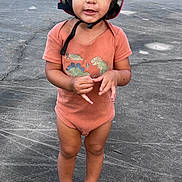 Elijahh joined the competition — help win amazing prizes! toddler, child, helmet, dinosaur, onesie, barefoot, outdoor, pavement, curious, standing, young_child, casual_clothing, playful, cute, small_person, person, expression, daylight, headgear, smile