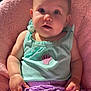 baby, child, chubby_cheeks, clothing, comfortable, curious_expression, cute, face, hand, indoors, infant, mint_green_top, pink_blanket, portrait, purple_clothing, seashell_patch, sitting, skin, soft_lighting, young