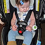 baby, child, car_seat, sleeping, pacifier, bottle, boots, blue_bow, clothing, straps, infant, seatbelt, indoor, warning_label, cute, adorable, child_safety, fringe_boots, resting, young