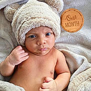 Dashiell is registered to the contest to win money with this photo: newborn, baby, infant, portrait, face, eyes, hat, bear_hat, blanket, fluffy, cozy, milestone, one_month, wooden_sign, indoor, lying_down, bare_chest, hand, cute, photography