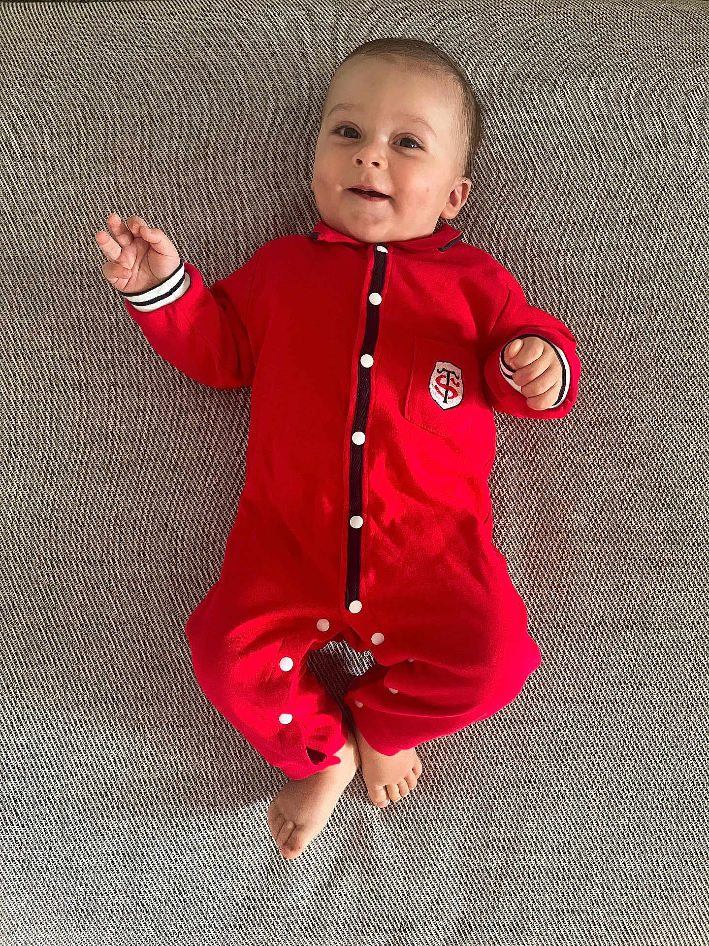 Roméo a rejoint le concours — aidez-le/la à gagner de superbes lots ! baby, infant, red_onesie, smiling, lying_down, barefoot, texture, fabric, indoor, cute, child, portrait, small_hands, small_feet, comfortable, casual, young, person, happy, cozy