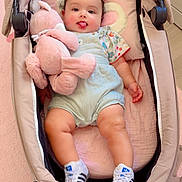 Layane participe au concours pour gagner de l'argent avec cette photo : baby, child, stroller, plush_toy, pink, sneakers, clothing, smiling, tongue_out, cute, indoor, floor, carpet, baby_clothes, person, toy, infant, seat, happy, small_child