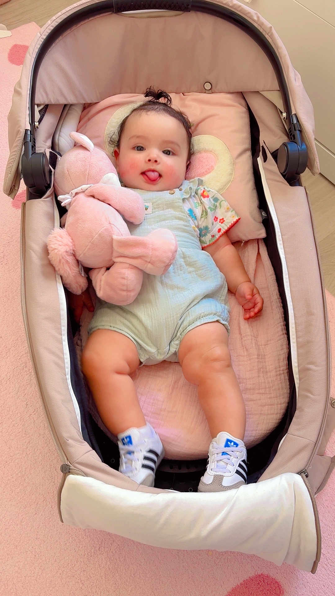 Layane participe au concours pour gagner de l'argent avec cette photo : baby, child, stroller, plush_toy, pink, sneakers, clothing, smiling, tongue_out, cute, indoor, floor, carpet, baby_clothes, person, toy, infant, seat, happy, small_child