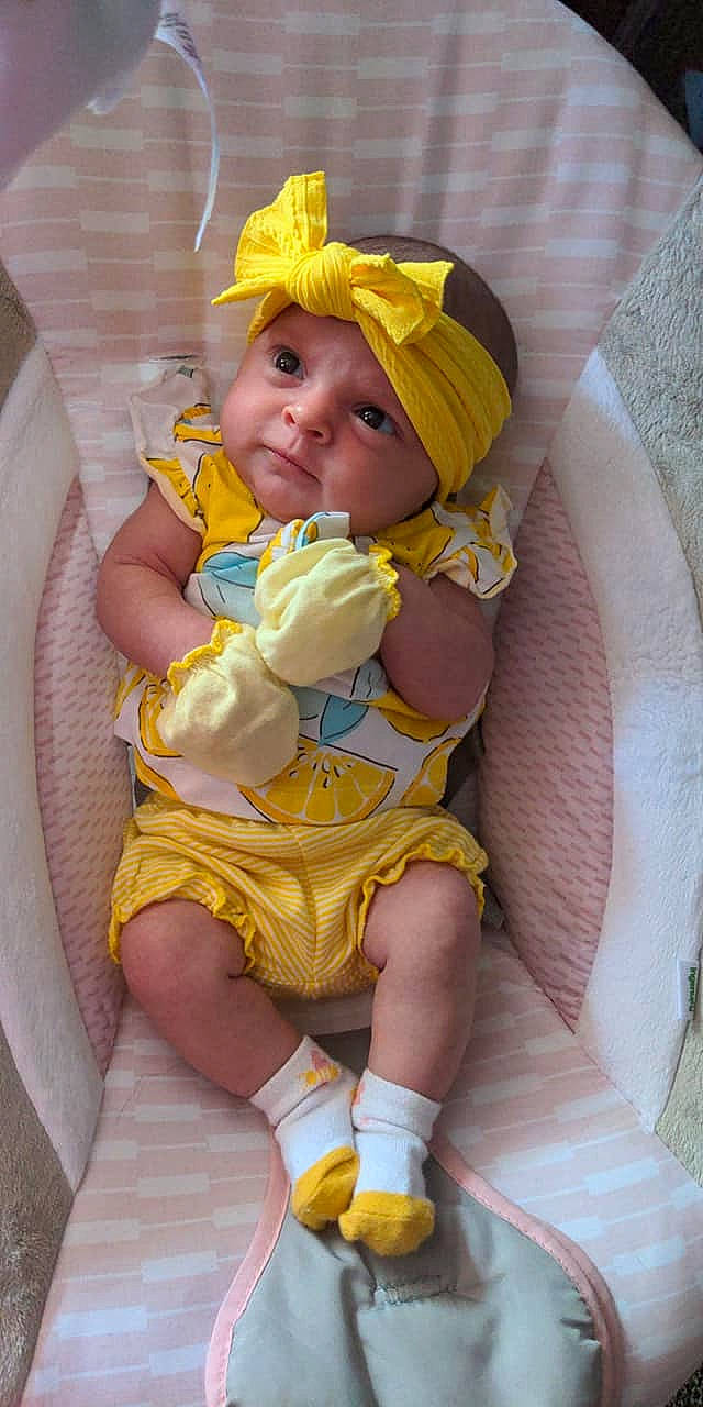 Phoebe joined the competition — help win amazing prizes! baby, baby_products, baby_toddler_clothing, chair, cheek, child, comfort, dress, finger, headgear, headwear, human_body, human_leg, lap, mouth, person, pink, purple, skin, thigh