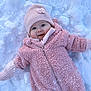 Katalya a rejoint le concours — aidez-le/la à gagner de superbes lots ! baby, pink_clothing, snowsuit, knit_hat, mittens, snow, outdoor, winter, child, smile, happy, face, cold_weather, infant, cute, frozen, playful, warm_clothing, lying_down, portrait