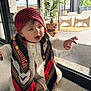 baby, basket, black, child, curious, floor, furniture, glass_door, gold_coins, home_interior, indoor, modern, plant, portrait, reaching_hand, red, rug, scarf, white_clothing, window