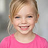 child, girl, smiling, portrait, blonde_hair, blue_eyes, pink_shirt, happy, face, head_and_shoulders, cute, young, human, person, eyelashes, teeth, casual_clothing, indoor, closeup, natural_light