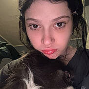 Big Ed is registered to the contest to win money with this photo: woman, dog, close_up, indoor, portrait, pet, black_hair, white_fur, face, animal, cuddling, casual_clothing, young_adult, expression, head_and_shoulders, nose_ring, dark_background, affection, relaxation, companion