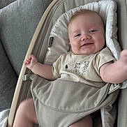 Bill is registered to the contest to win money with this photo: baby, infant, smile, face, tshirt, animal_print, baby_seat, cushion, furniture, living_room, home_interior, patterned_wall, soft_toys, child, cute, comfort, relaxing, happy, person, indoors