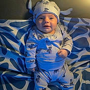 Santino a rejoint le concours — aidez-le/la à gagner de superbes lots ! baby, infant, child, pajamas, hat, cute, smiling, face, patterned_blanket, pillow, indoor, cozy, soft_light, blue, white, sitting, clothing, foot, portrait, expression