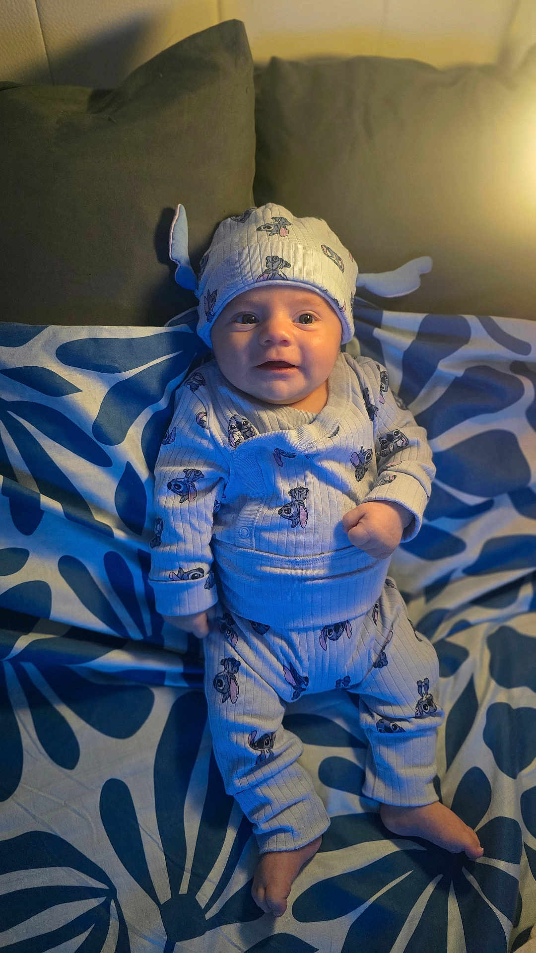 Santino a rejoint le concours — aidez-le/la à gagner de superbes lots ! baby, infant, child, pajamas, hat, cute, smiling, face, patterned_blanket, pillow, indoor, cozy, soft_light, blue, white, sitting, clothing, foot, portrait, expression