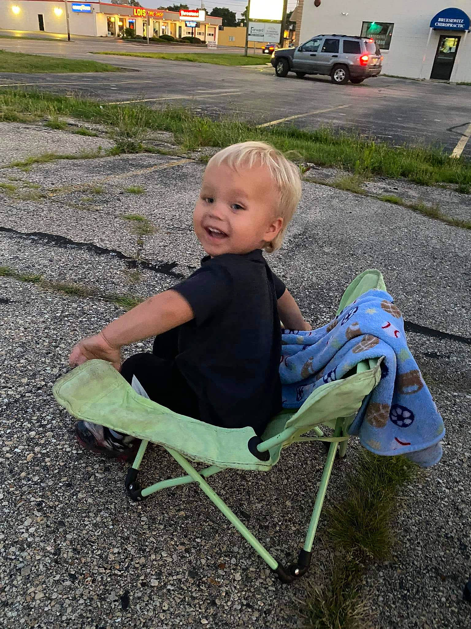Adonis is registered to the contest to win money with this photo: asphalt, automotive_lighting, car, chair, child, comfort, fun, grass, leaf, leisure, outdoor_furniture, person, plant, recreation, road_surface, sitting, smile, tire, toddler, truck